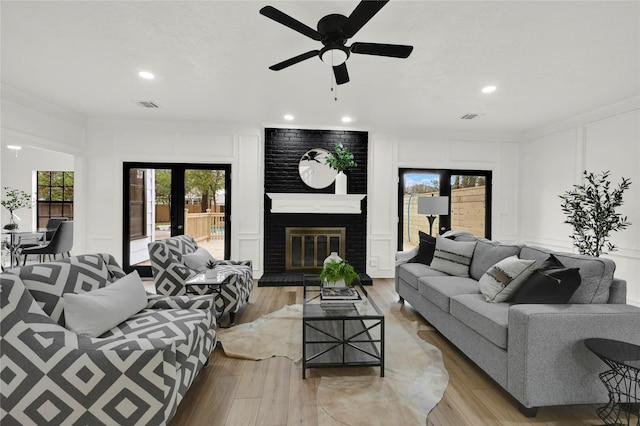 living room featuring a fireplace, light hardwood / wood-style floors, and ceiling fan