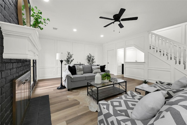 living room featuring ceiling fan, a fireplace, and hardwood / wood-style flooring