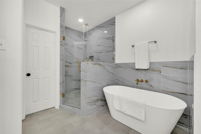 bathroom featuring tile patterned flooring, shower with separate bathtub, a textured ceiling, and tile walls