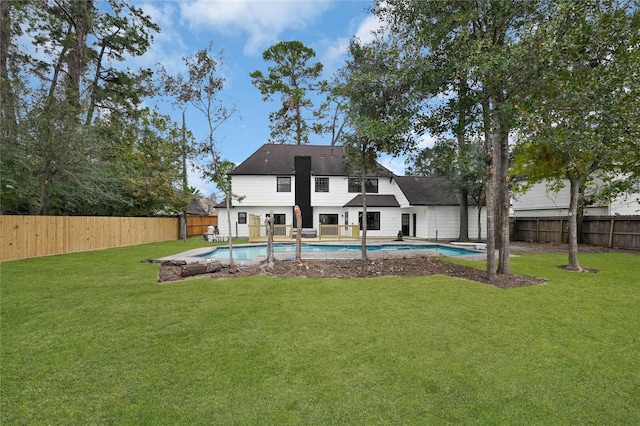 back of property with a fenced in pool and a lawn