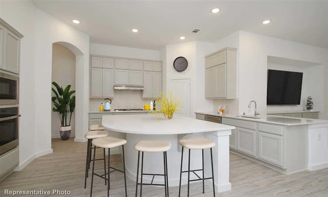 kitchen featuring backsplash, light hardwood / wood-style floors, stainless steel appliances, sink, and gray cabinets