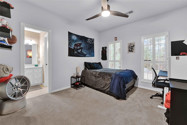 bedroom with ensuite bathroom, ceiling fan, and light colored carpet