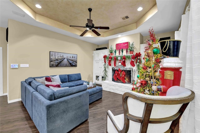 living room featuring dark hardwood / wood-style floors, a raised ceiling, and ceiling fan