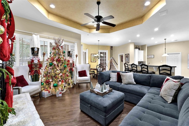 living room featuring a raised ceiling, dark hardwood / wood-style flooring, and ceiling fan with notable chandelier