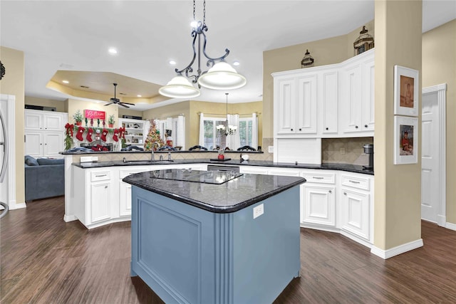 kitchen with kitchen peninsula, ceiling fan, dark wood-type flooring, white cabinetry, and a kitchen island