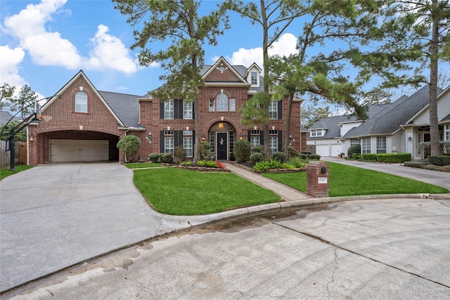 colonial inspired home with a front lawn, concrete driveway, and brick siding