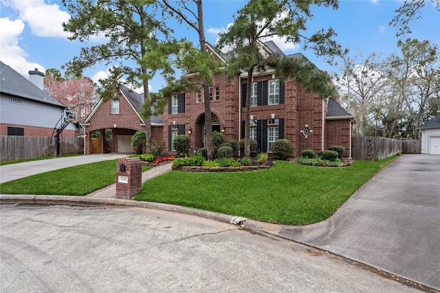 colonial inspired home with a front lawn, fence, concrete driveway, a garage, and brick siding