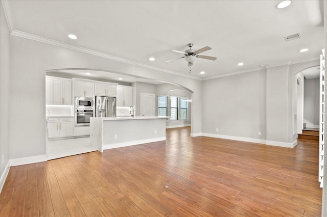 unfurnished living room with ceiling fan, crown molding, light hardwood / wood-style floors, and sink