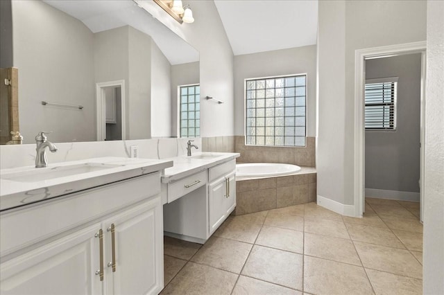 bathroom featuring tile patterned flooring, a relaxing tiled tub, lofted ceiling, and vanity