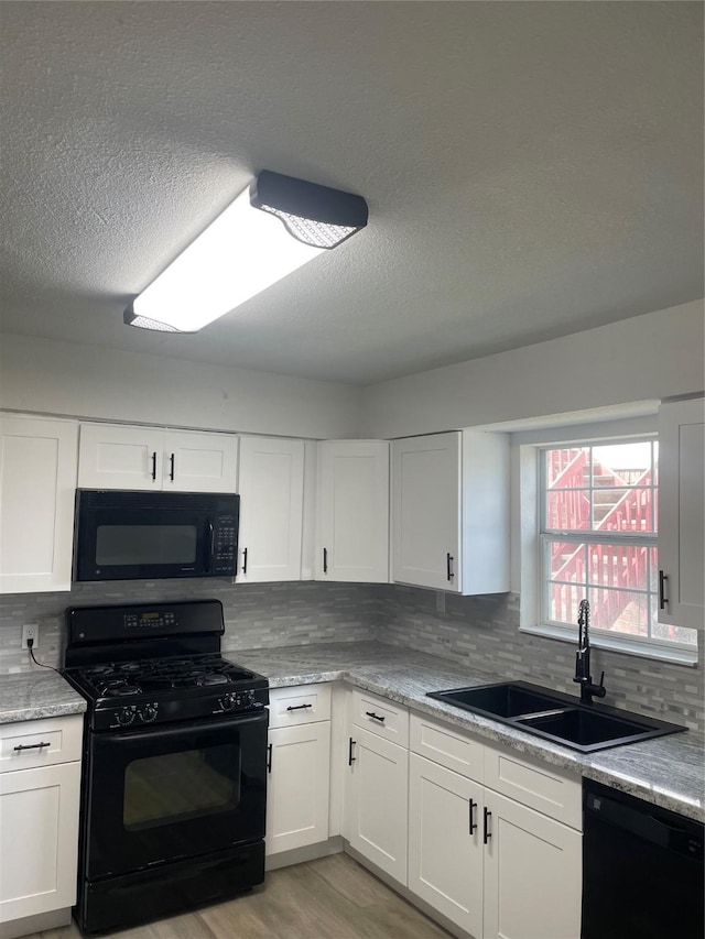 kitchen with black appliances, white cabinets, sink, light wood-type flooring, and tasteful backsplash