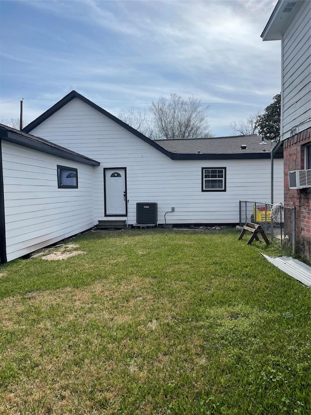 rear view of house with a yard, cooling unit, and central air condition unit