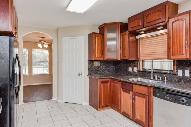 kitchen featuring ceiling fan, sink, black fridge, stainless steel dishwasher, and dark stone counters