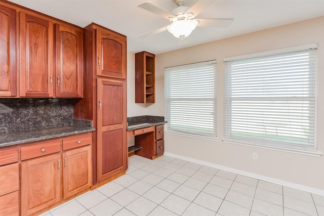 kitchen featuring decorative backsplash, a healthy amount of sunlight, built in desk, and dark stone counters