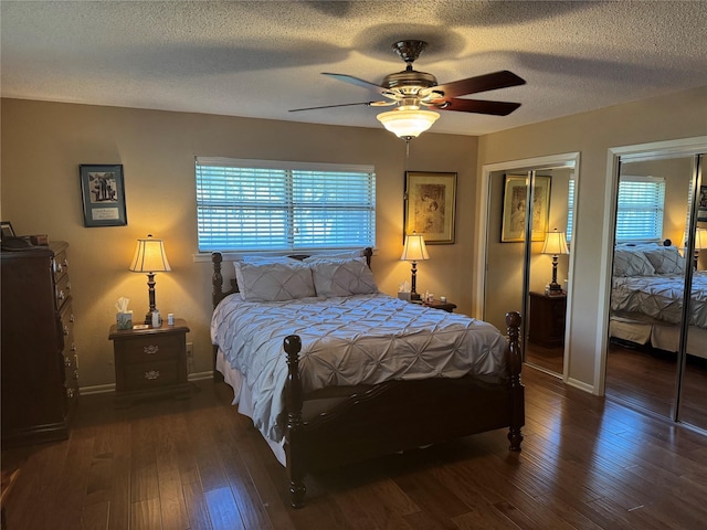 bedroom featuring multiple closets, ceiling fan, dark hardwood / wood-style flooring, and a textured ceiling