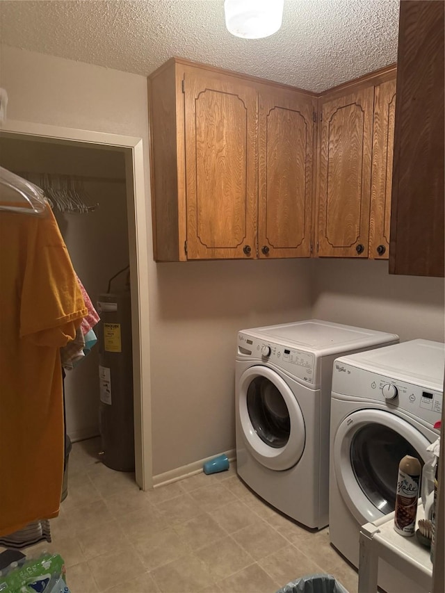 washroom with cabinets, electric water heater, a textured ceiling, and separate washer and dryer