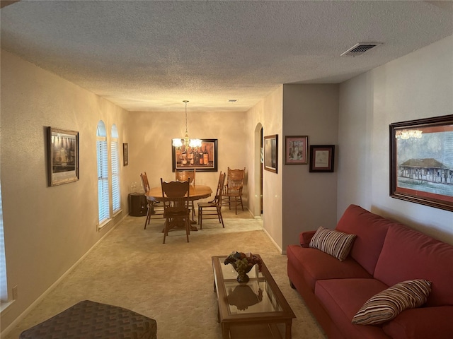 living room with light colored carpet, a textured ceiling, and a chandelier