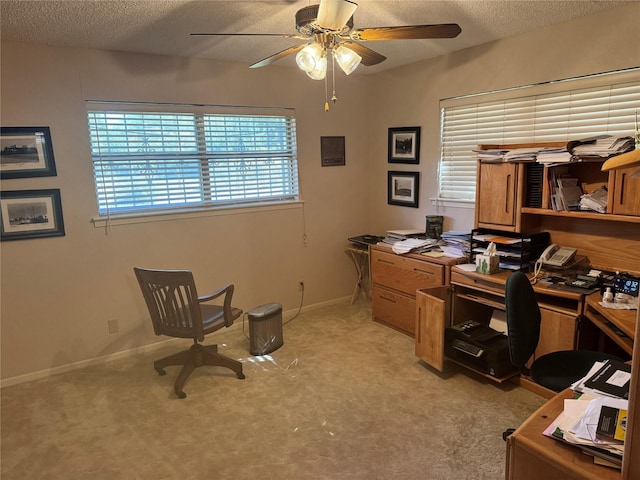 carpeted home office with ceiling fan and a textured ceiling