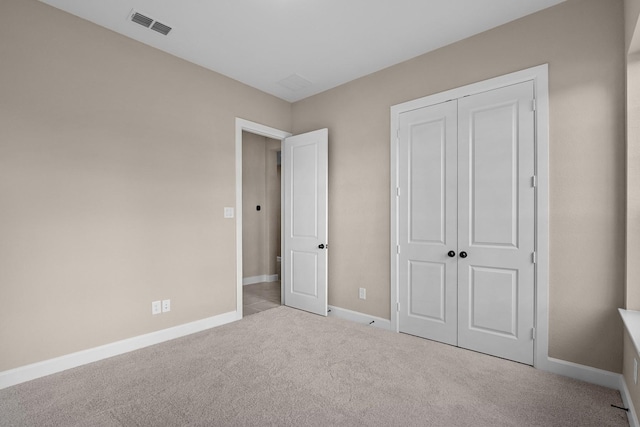 unfurnished bedroom featuring light carpet and a closet