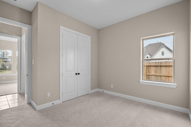 unfurnished bedroom featuring light carpet and a closet