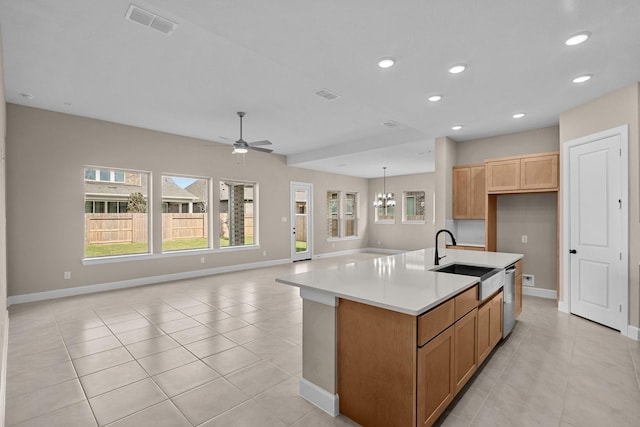 kitchen with stainless steel dishwasher, ceiling fan with notable chandelier, sink, light tile patterned floors, and a center island with sink