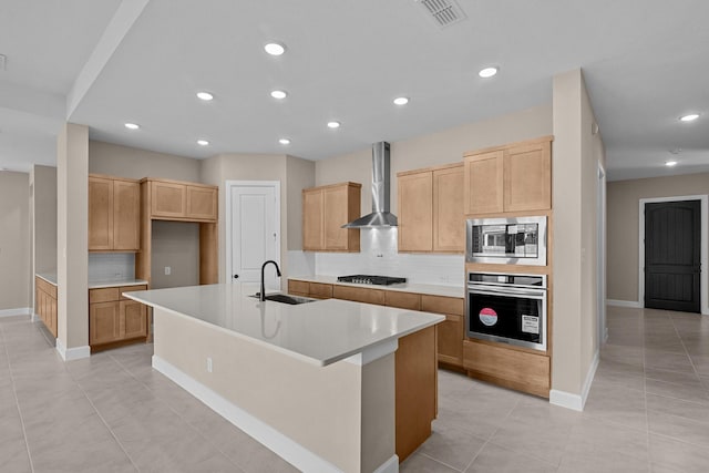 kitchen with sink, wall chimney exhaust hood, a kitchen island with sink, stainless steel appliances, and decorative backsplash