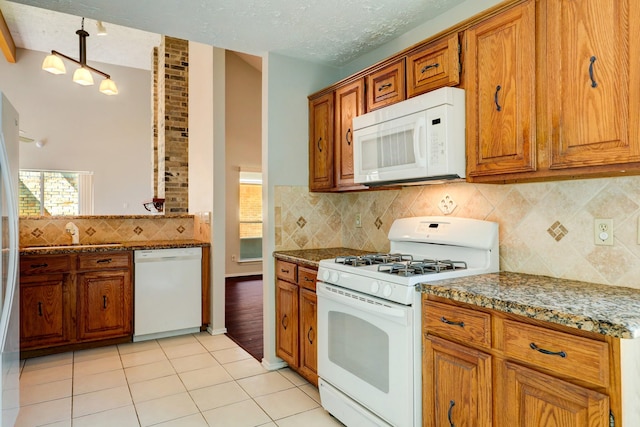 kitchen with light stone counters, pendant lighting, a textured ceiling, white appliances, and light tile patterned flooring