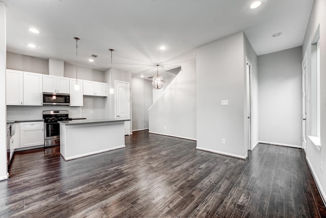 kitchen featuring appliances with stainless steel finishes, decorative light fixtures, white cabinetry, and dark hardwood / wood-style floors