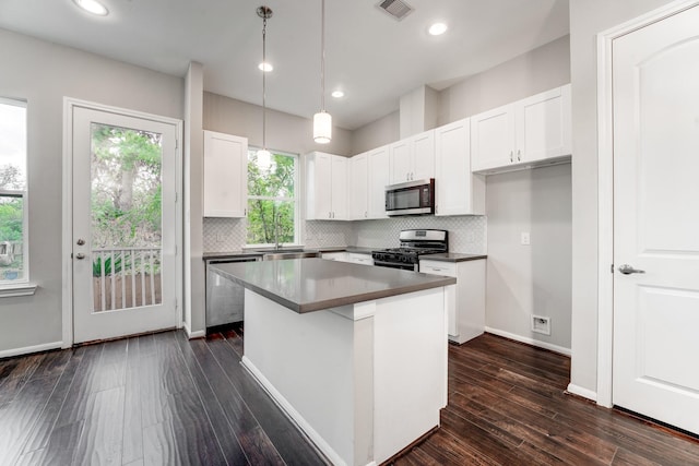 kitchen with a kitchen island, white cabinetry, stainless steel appliances, and dark wood-type flooring