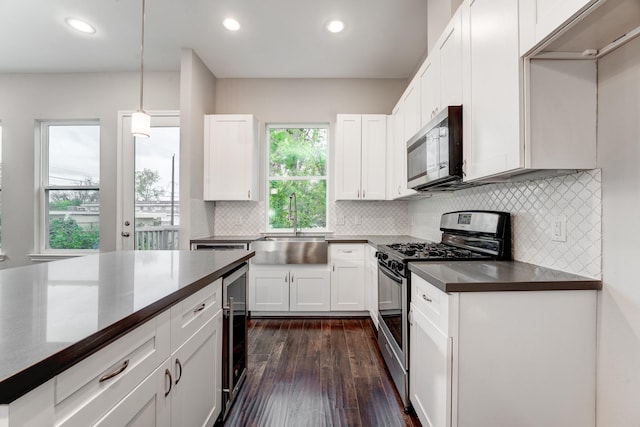 kitchen with stainless steel appliances, dark wood-type flooring, sink, white cabinetry, and hanging light fixtures