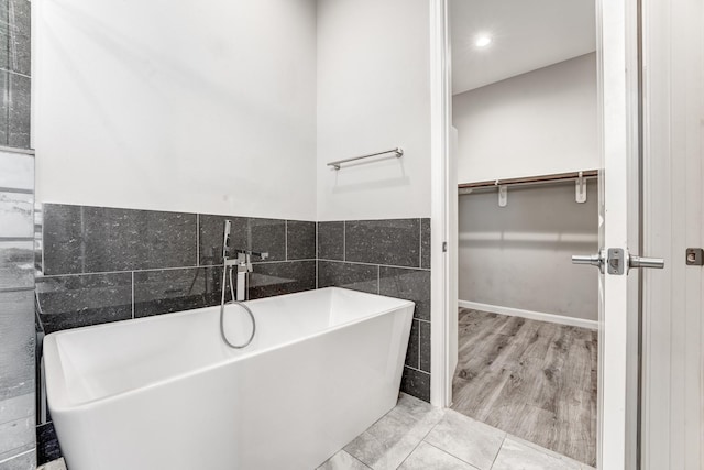 bathroom with hardwood / wood-style floors, a bathtub, and tile walls