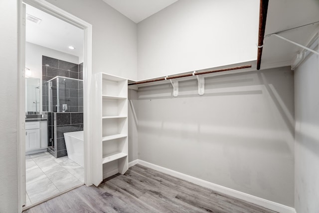 walk in closet with light hardwood / wood-style floors