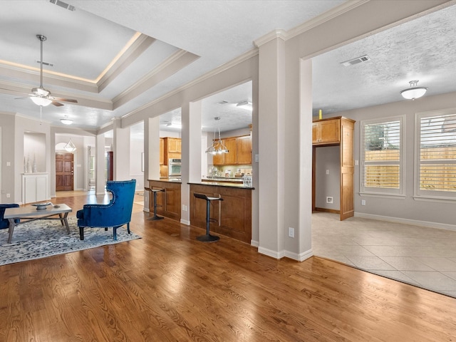 living room with wood-type flooring, ceiling fan with notable chandelier, a textured ceiling, and crown molding