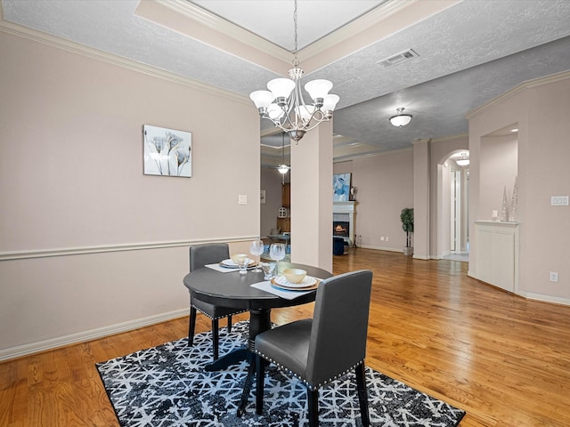 dining area with hardwood / wood-style flooring, crown molding, a textured ceiling, and an inviting chandelier