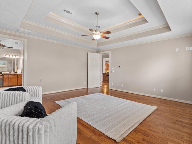 sitting room with hardwood / wood-style flooring, a raised ceiling, and ornamental molding