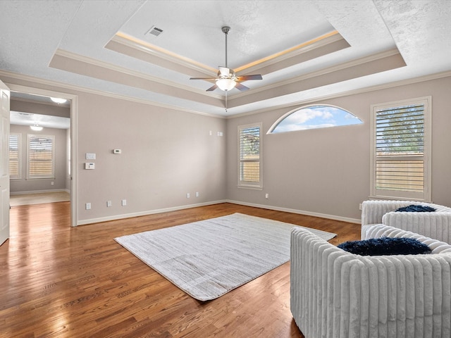 sitting room featuring hardwood / wood-style floors, ceiling fan, ornamental molding, a textured ceiling, and a tray ceiling