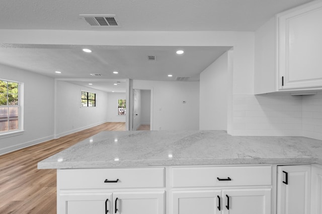 kitchen featuring white cabinetry, light stone counters, tasteful backsplash, and light wood-type flooring