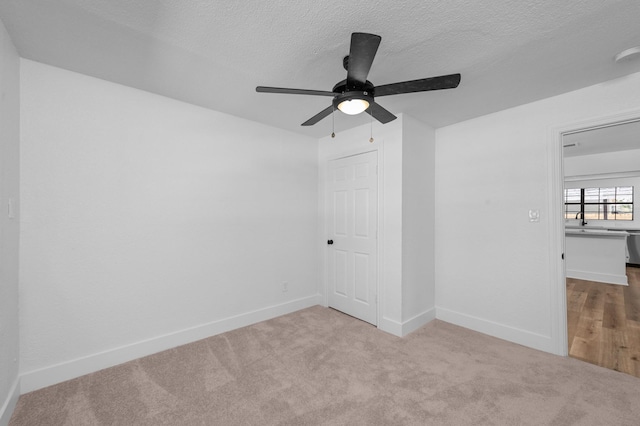 carpeted empty room featuring ceiling fan, sink, and a textured ceiling