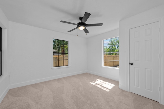 spare room featuring light colored carpet and ceiling fan