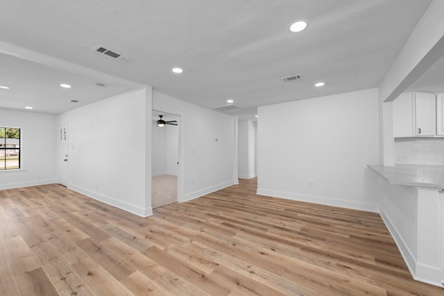 unfurnished room featuring ceiling fan, light wood-type flooring, and a textured ceiling