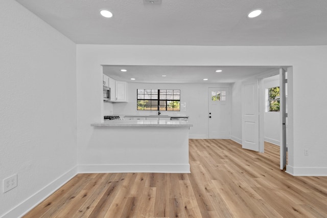 kitchen featuring plenty of natural light, white cabinetry, kitchen peninsula, and light hardwood / wood-style flooring