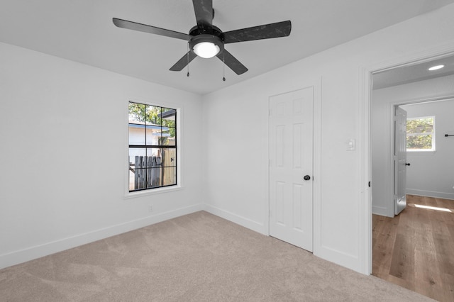 unfurnished bedroom with multiple windows, ceiling fan, and light colored carpet