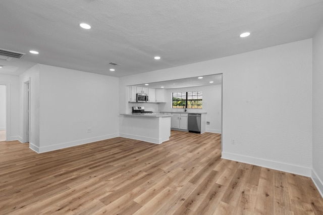 unfurnished living room featuring a textured ceiling and light wood-type flooring