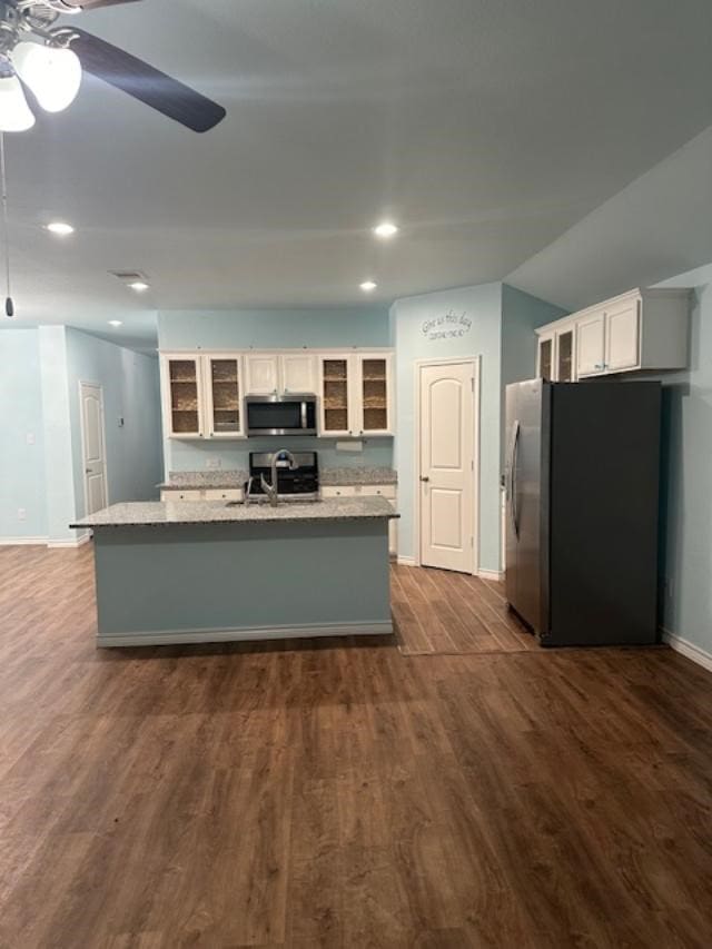 kitchen with appliances with stainless steel finishes, dark wood-type flooring, sink, white cabinetry, and an island with sink