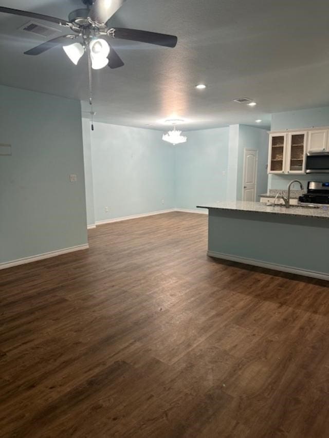 unfurnished living room featuring ceiling fan with notable chandelier, dark hardwood / wood-style flooring, and sink