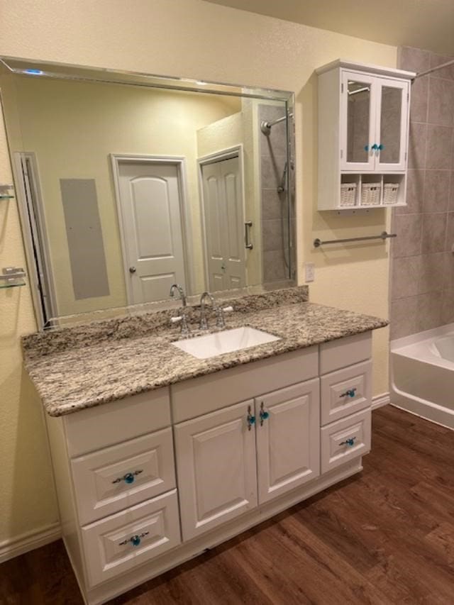 bathroom with vanity, wood-type flooring, and tiled shower / bath