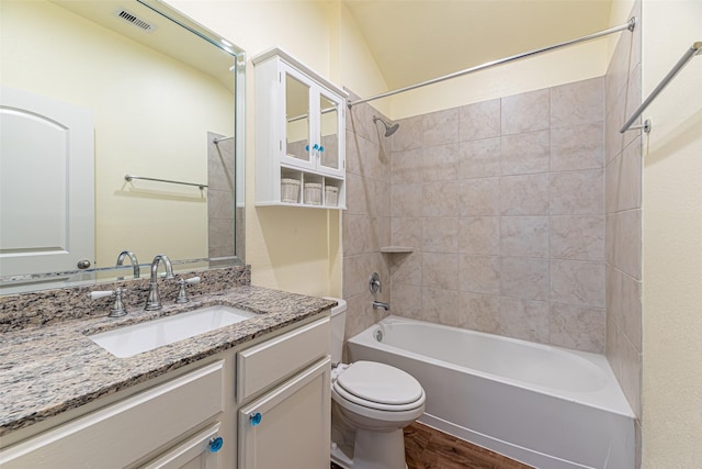 full bathroom featuring tiled shower / bath, lofted ceiling, toilet, vanity, and hardwood / wood-style flooring