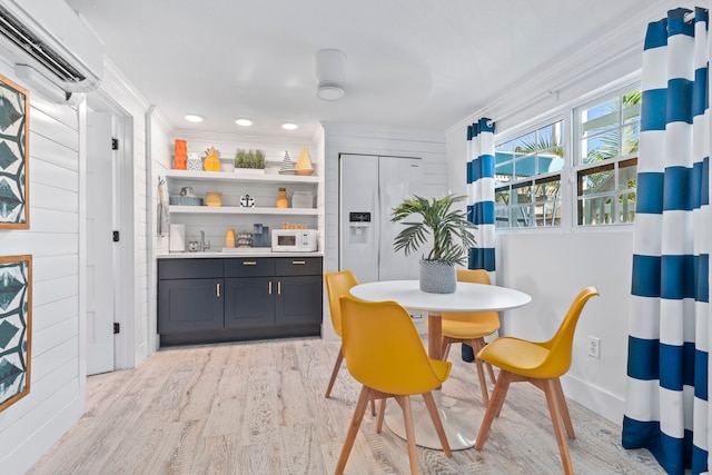 dining area with light hardwood / wood-style floors, ornamental molding, sink, and a wall unit AC