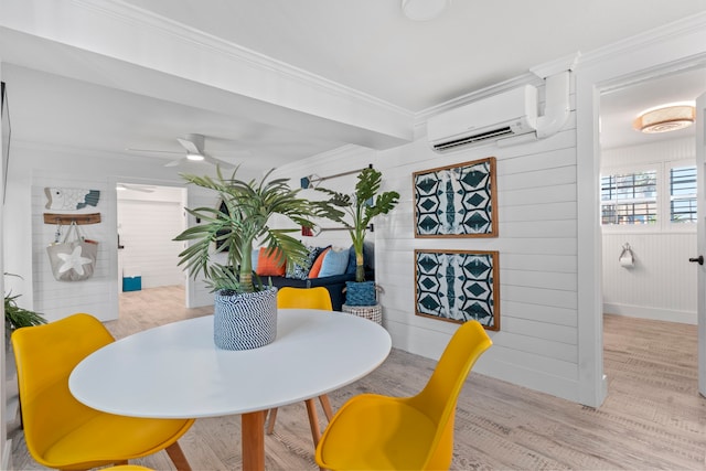 dining space featuring wooden walls, ceiling fan, ornamental molding, light hardwood / wood-style floors, and a wall unit AC