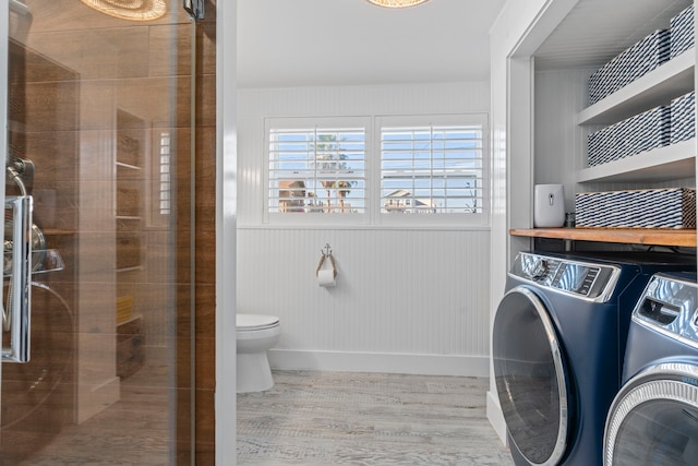 interior space featuring wooden walls, washer and dryer, a shower with shower door, and toilet