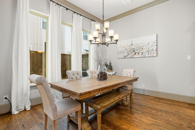 dining area featuring crown molding, wood-type flooring, and a chandelier